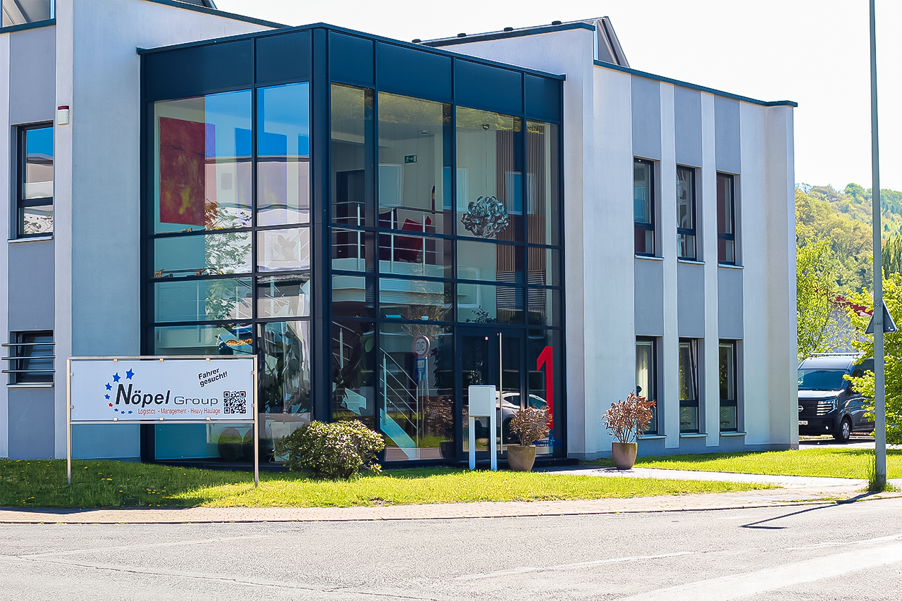 Repr&auml;sentatives B&uuml;rogeb&auml;ude der N&ouml;pel Group mit moderner Glasfassade und Firmenschild f&uuml;r Logistik und Schwertransporte.